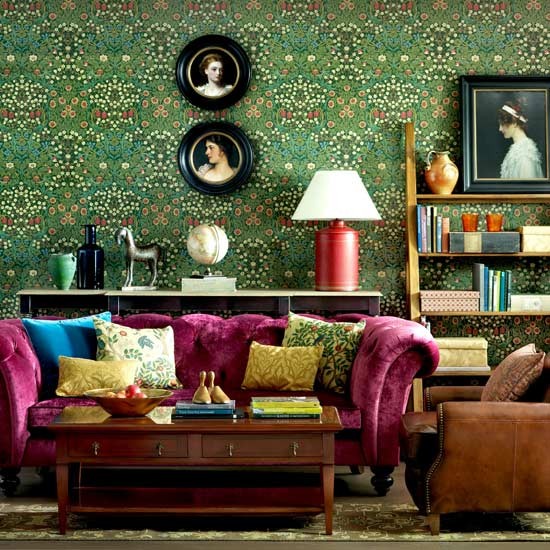 Magenta pink Chesterfield sofa in a designer living room. Fantastic emerald green wallpaper